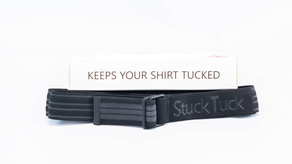 Black Stuck Tuck shirt stay belt in front of its white retail box